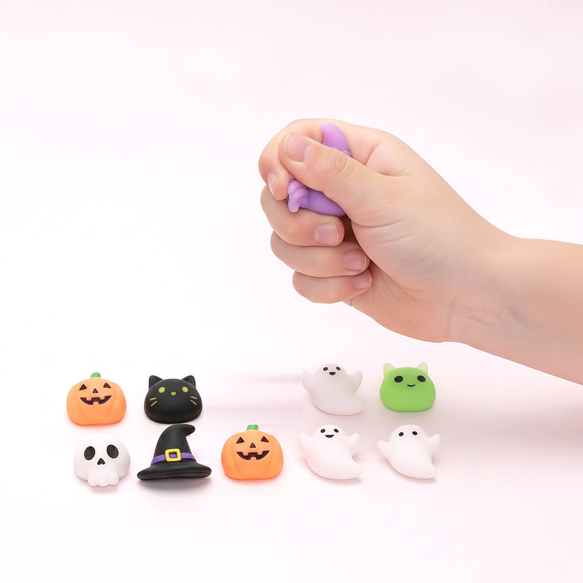 Mini mochi Halloween pressé dans une main d'enfant, les 9 autres mochis devant