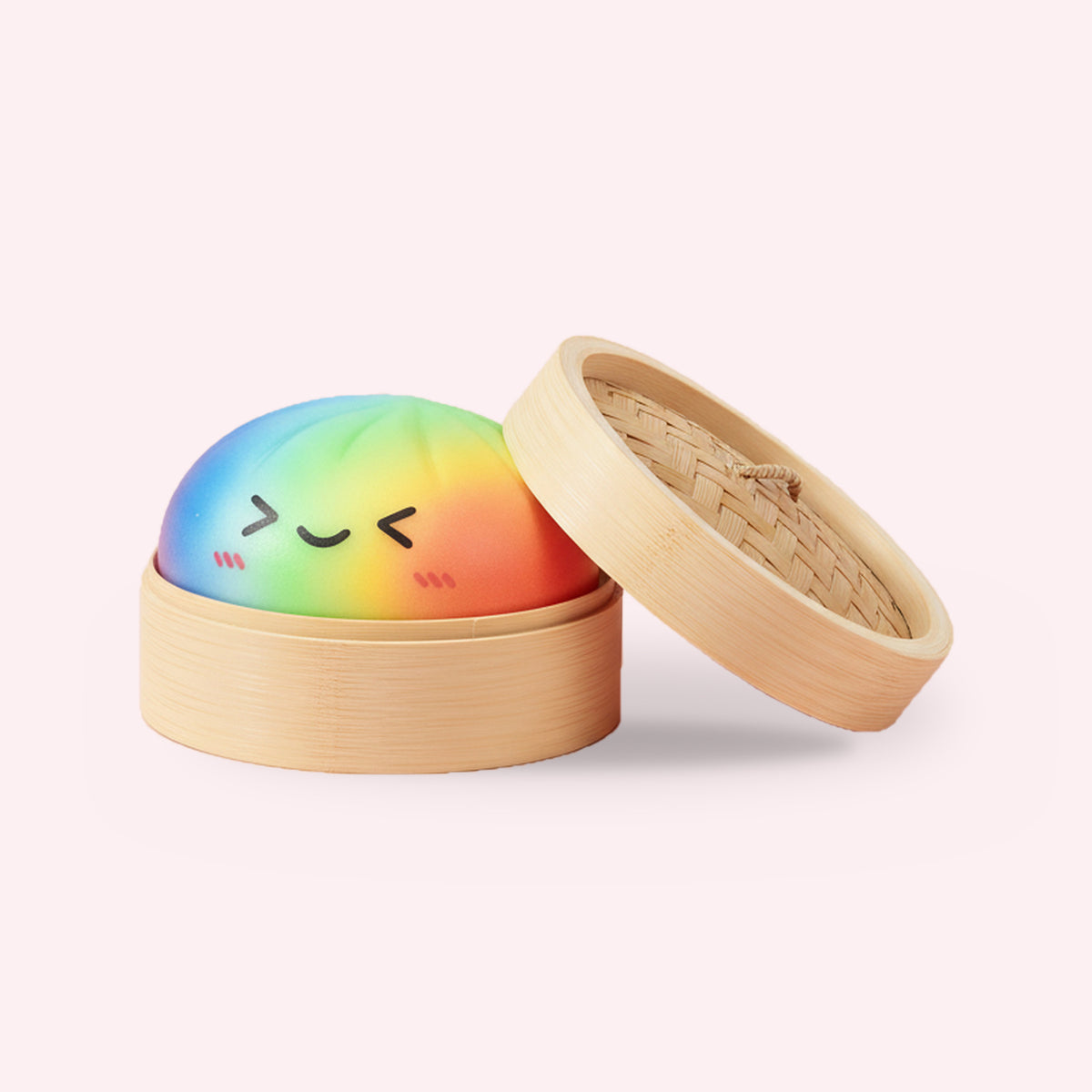 Squishy géant ravioli vapeur arc-en-ciel dans son panier en bambou, packshot sur fond rose clair